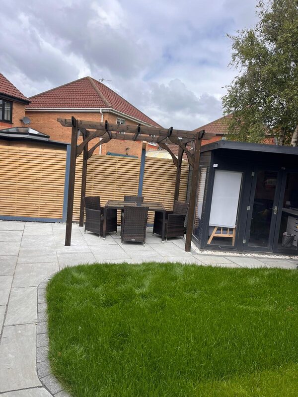 Finished garden with timber pergola, outdoor dining set, lawn and garden cabin