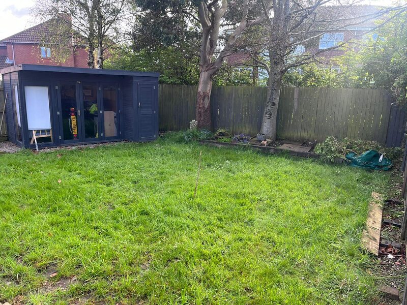 Back garden before landscaping transformation showing overgrown lawn and garden cabin