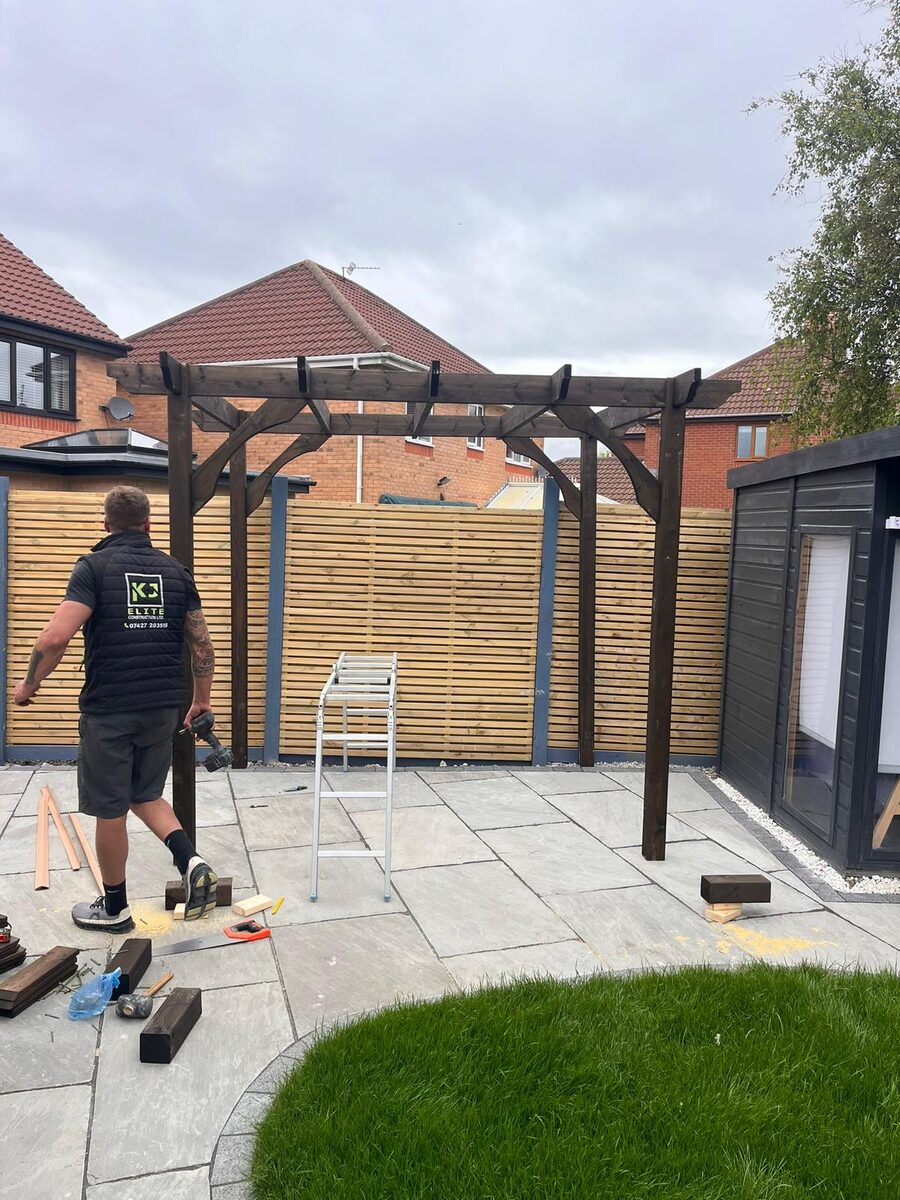 KJ Elite Construction worker building timber pergola on stone patio in Blackpool