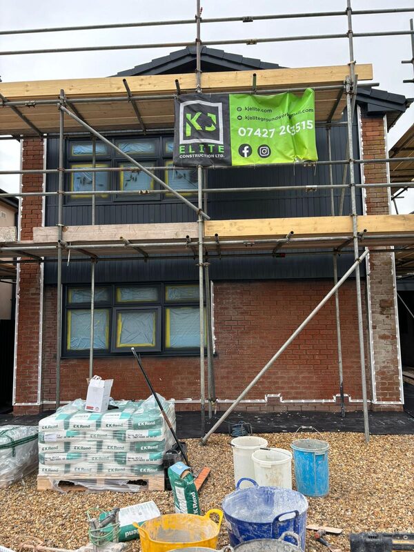 House renovation in progress with scaffolding and KJ Elite Construction banner